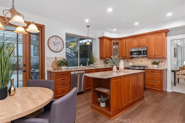 a kitchen with stainless steel appliances granite countertop a stove a sink dishwasher a dining table and chairs with wooden floor