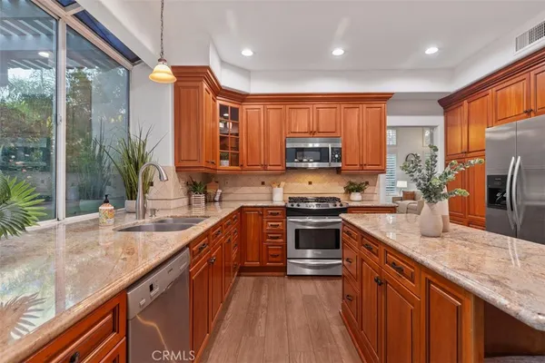 a kitchen with stainless steel appliances granite countertop a sink a stove and a wooden floors