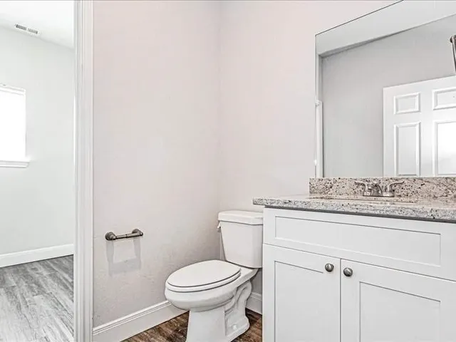 a bathroom with a granite countertop toilet and a sink