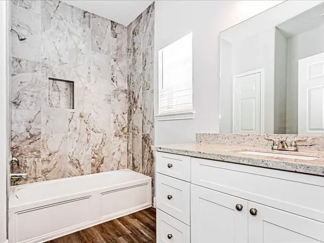 a bathroom with a granite countertop sink and a bathtub