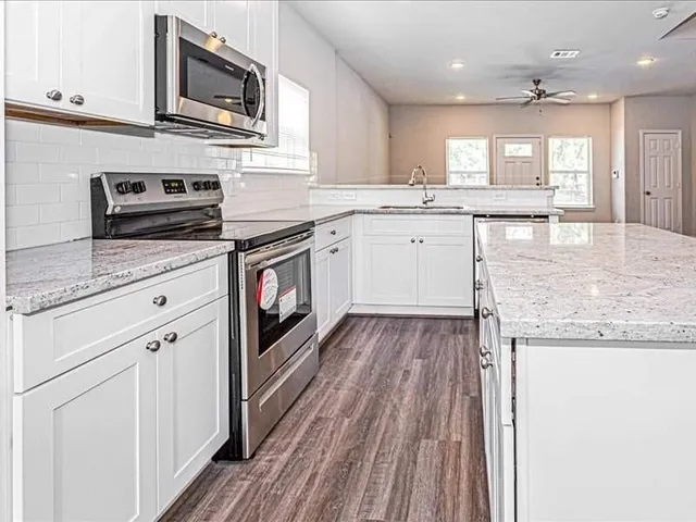 a kitchen with stainless steel appliances granite countertop a stove a sink and a microwave