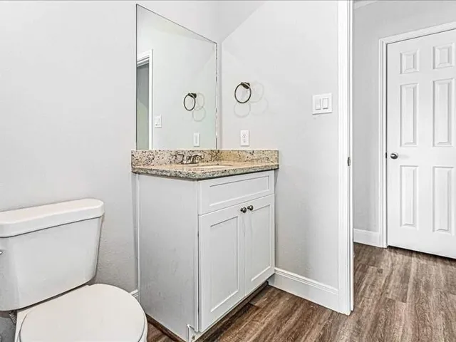 a bathroom with a granite countertop toilet a sink and a mirror