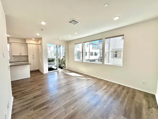 a view of empty room with wooden floor and kitchen