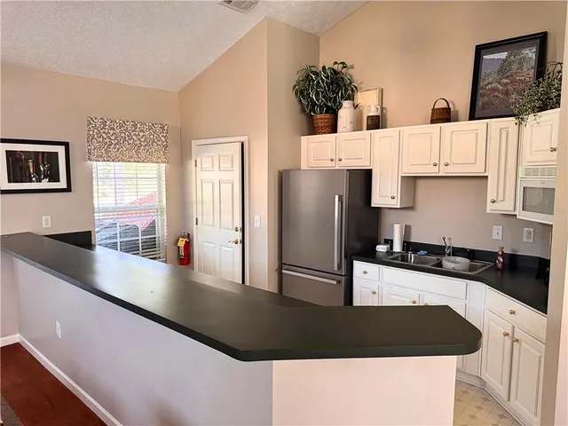 a kitchen with stainless steel appliances granite countertop a refrigerator a stove and a sink with wooden floor
