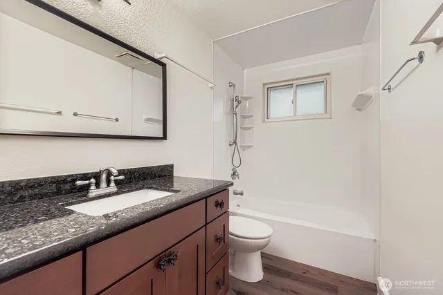 a bathroom with a granite countertop sink a toilet and bathtub