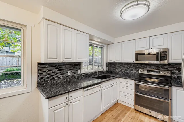 a kitchen with granite countertop a sink stainless steel appliances and cabinets