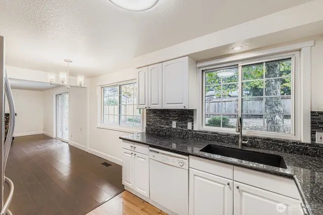 a kitchen with granite countertop a sink and a white wooden cabinets