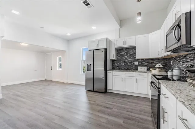 a kitchen with granite countertop a refrigerator stove top oven and sink