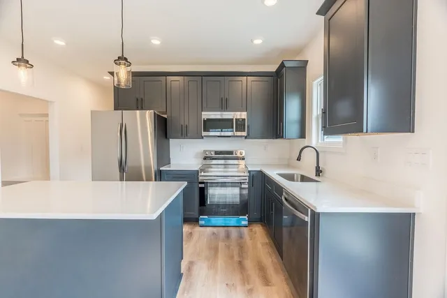 a kitchen with stainless steel appliances granite countertop a sink stove and refrigerator