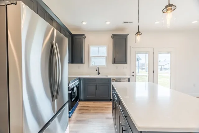 a large kitchen with a sink a refrigerator and a stove top oven