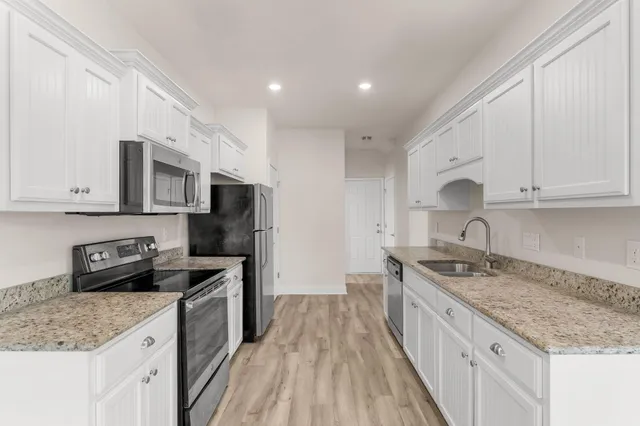 a kitchen with stainless steel appliances granite countertop a sink stove microwave and refrigerator