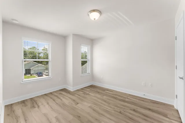 an empty room with wooden floor and windows