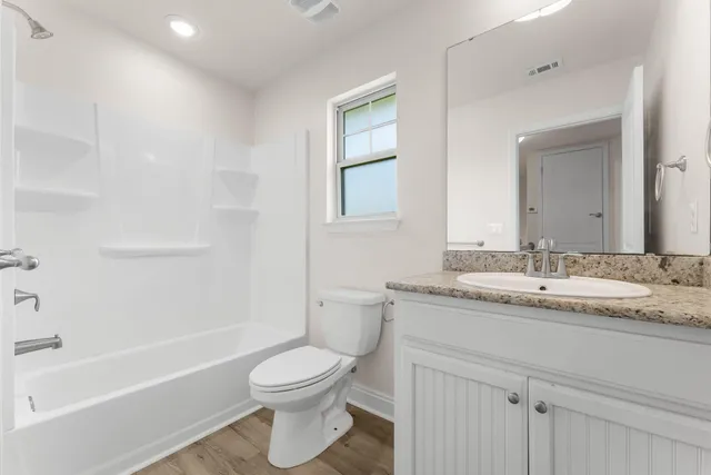 a bathroom with a granite countertop toilet a sink and a bathtub