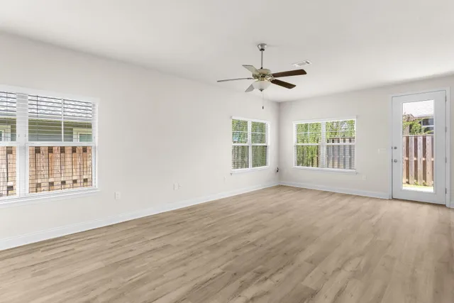 a view of an empty room with a window and wooden floor