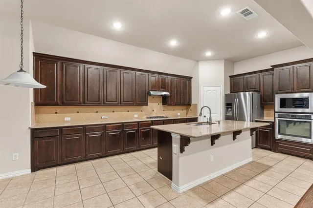 a kitchen with kitchen island granite countertop stainless steel appliances and cabinets