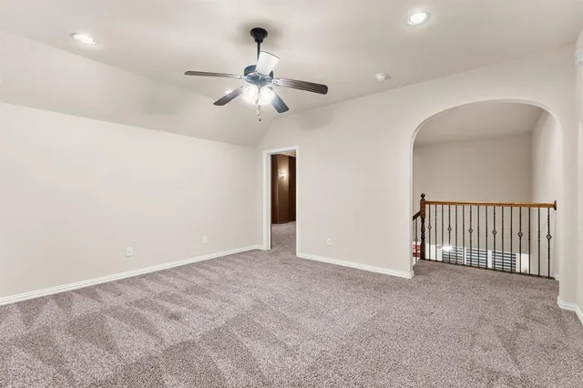 an empty room with chandelier fan and windows