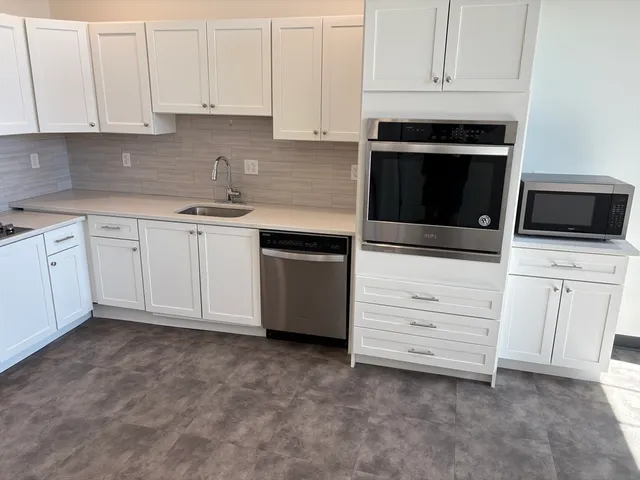 a kitchen with white cabinets and stainless steel appliances