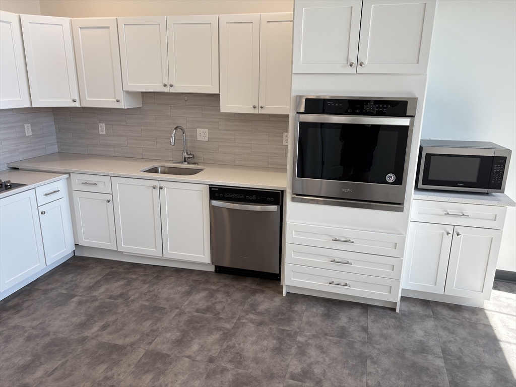 151 Chestnut Street, Unit 413 Springfield, MA 01103 - Photo 1 of 11 a kitchen with white cabinets and stainless steel appliances