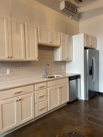 a kitchen with stainless steel appliances granite countertop white cabinets a refrigerator and a sink