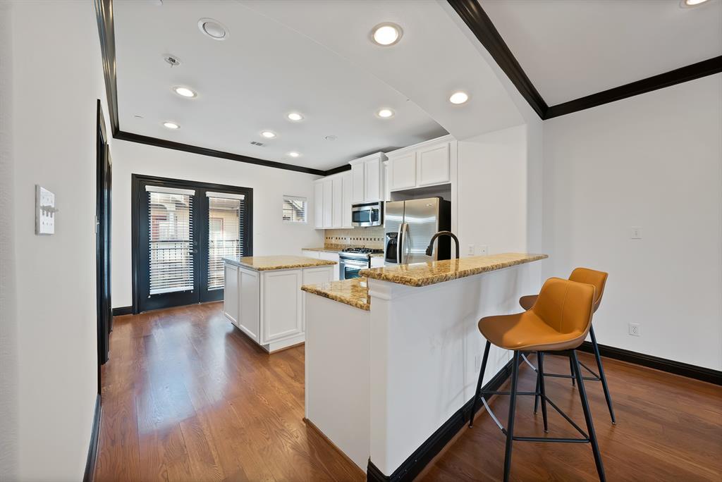 5747 Prospect Avenue, Unit B Dallas, TX 75206 - Photo 16 of 39 a kitchen with stainless steel appliances kitchen island granite countertop wooden floors and white cabinets