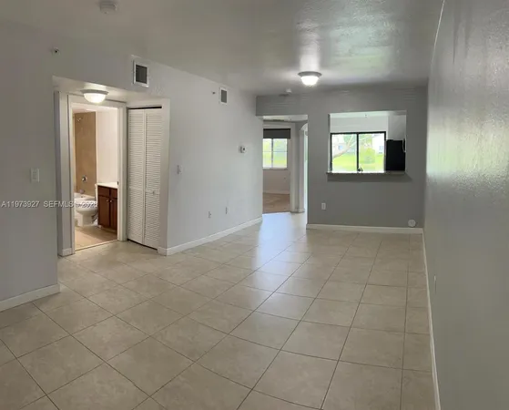 a view of an empty room with window and bathroom