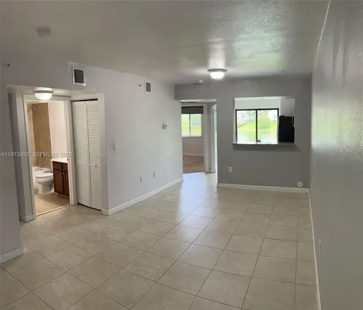a view of an empty room with glass door and a bathroom