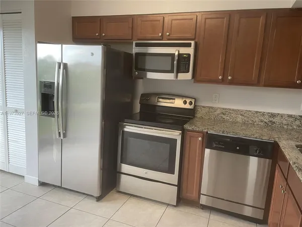 a kitchen with stainless steel appliances granite countertop a refrigerator and a microwave