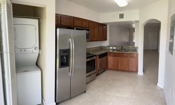 a kitchen with stainless steel appliances granite countertop a refrigerator a stove and a sink