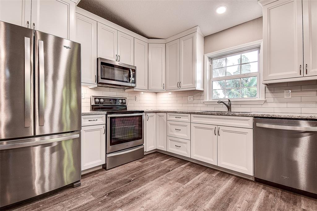 289 Whisper Lake Road Palm Harbor, FL 34683 - Photo 19 of 40 a kitchen with granite countertop a refrigerator stove and microwave