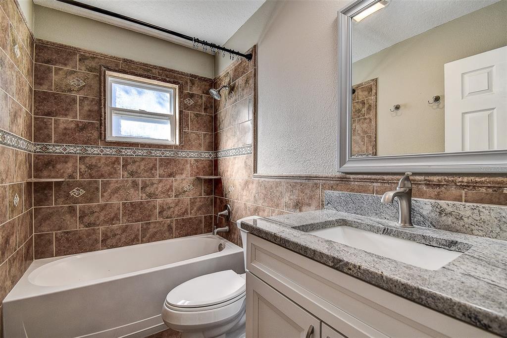 289 Whisper Lake Road Palm Harbor, FL 34683 - Photo 24 of 40 a bathroom with a granite countertop toilet a sink and bathtub