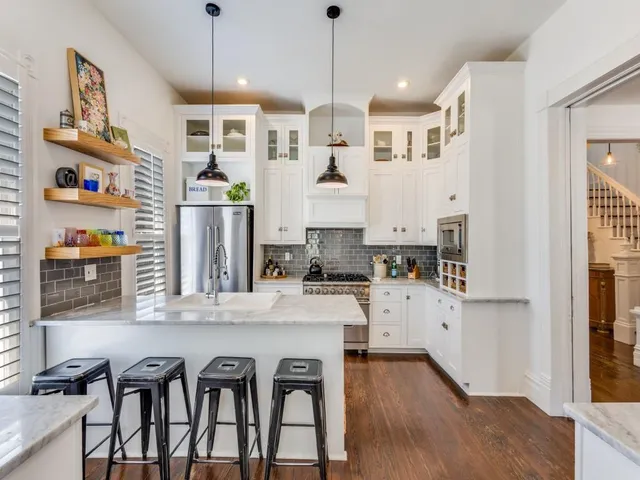 a kitchen with stainless steel appliances granite countertop a sink dishwasher and white cabinets with wooden floor
