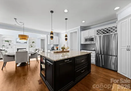 a kitchen with stainless steel appliances granite countertop a stove a refrigerator a kitchen island a sink dishwasher and a dining table with wooden floor