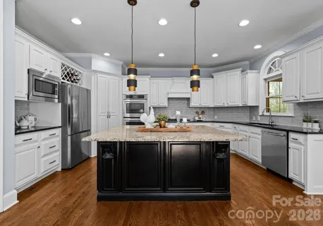a kitchen with stainless steel appliances granite countertop a sink a stove a refrigerator and island with wooden floor