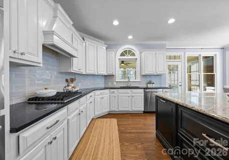 a kitchen with granite countertop stainless steel appliances a sink stove top oven and cabinets