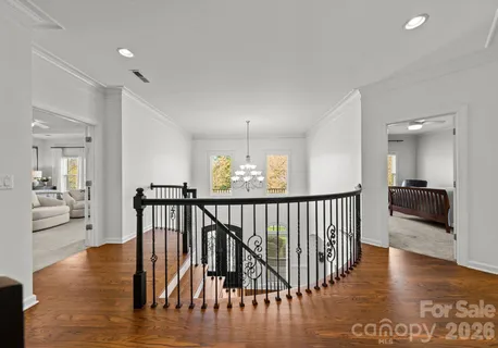 a view of a hallway with wooden floor and windows