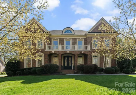 a front view of a house with garden and trees