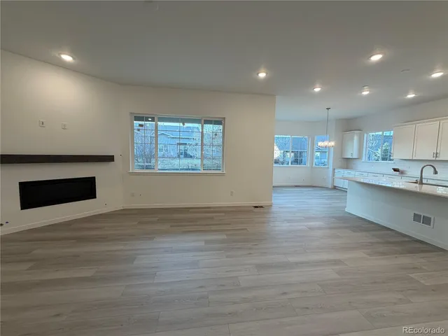 a view of an empty room with a kitchen and a window