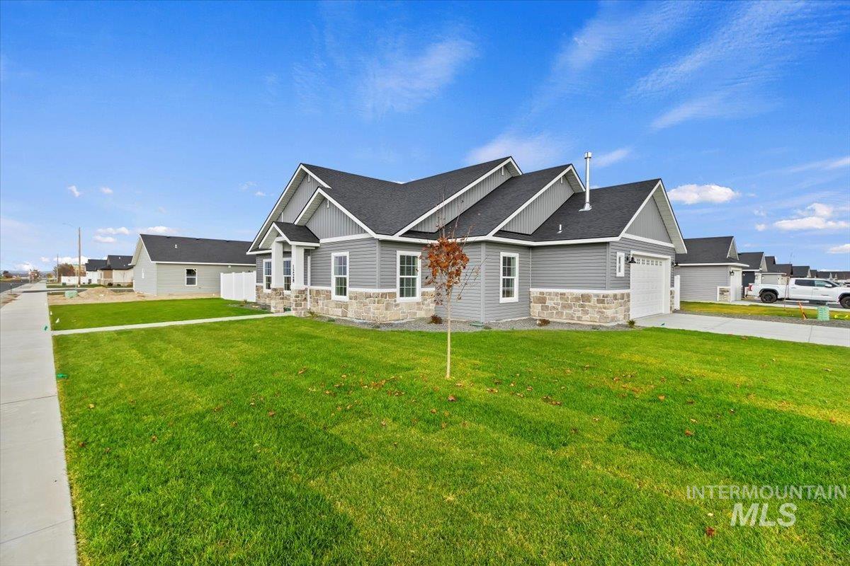 1228 Creekside Way Twin Falls, ID 83301 - Photo 1 of 28 Craftsman-style home featuring stone siding, a front yard, roof with shingles, and concrete driveway