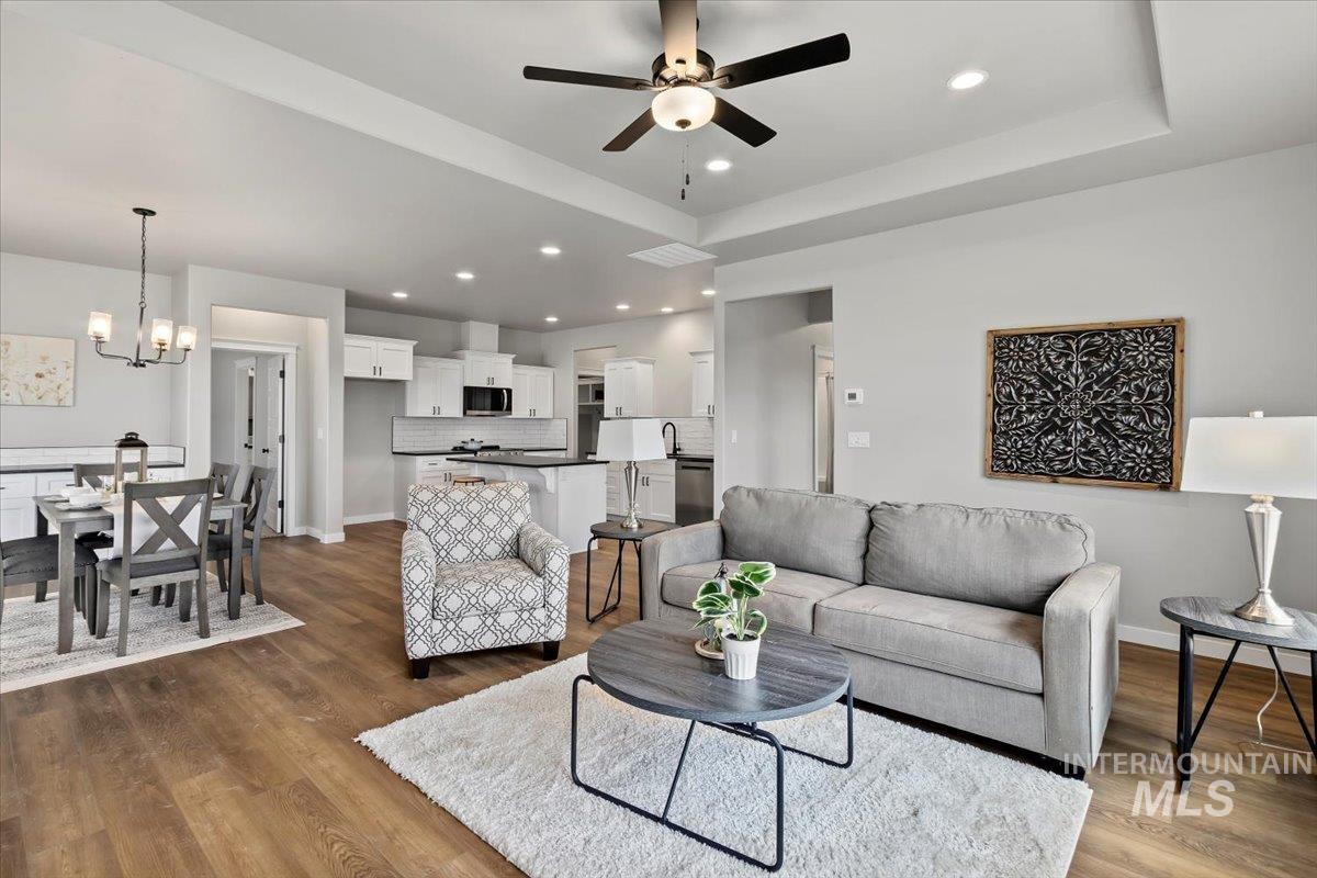 1228 Creekside Way Twin Falls, ID 83301 - Photo 4 of 28 Living area with a raised ceiling, dark wood finished floors, recessed lighting, a ceiling fan, and a chandelier