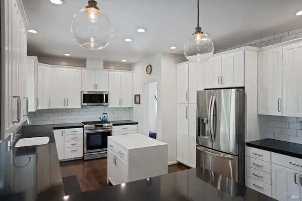 a kitchen with stainless steel appliances white cabinets and a stove top oven