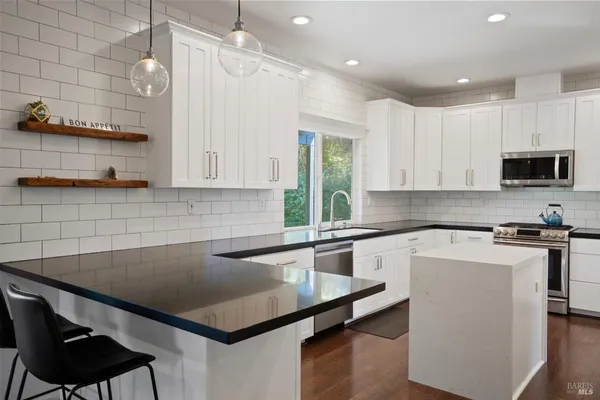 a kitchen with granite countertop a counter space a refrigerator a stove a sink and cabinets