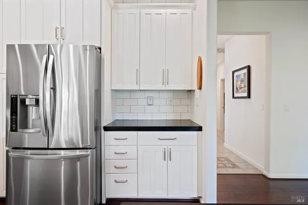 a kitchen with stainless steel appliances a refrigerator a sink dishwasher a oven with white cabinets and wooden floor