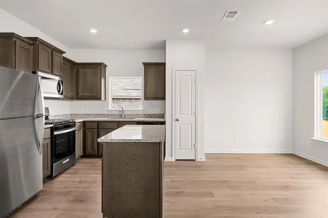 a kitchen with stainless steel appliances granite countertop a refrigerator a sink and a stove