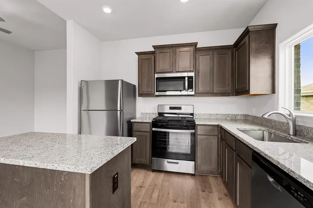 a kitchen with kitchen island granite countertop a sink dishwasher stove and refrigerator