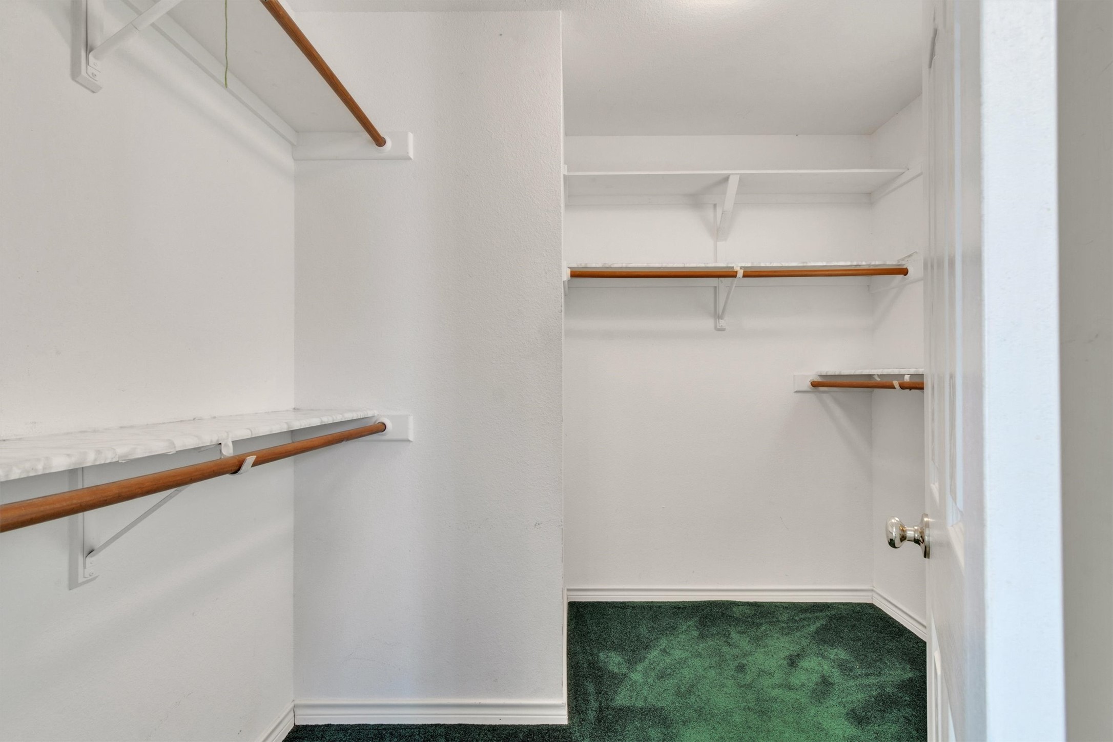 1207 Orlando Road Austin, TX 78733 - Photo 16 of 30 Walk-in closet featuring built-in shelving, wood-finish hanging rods, and dark green carpeting