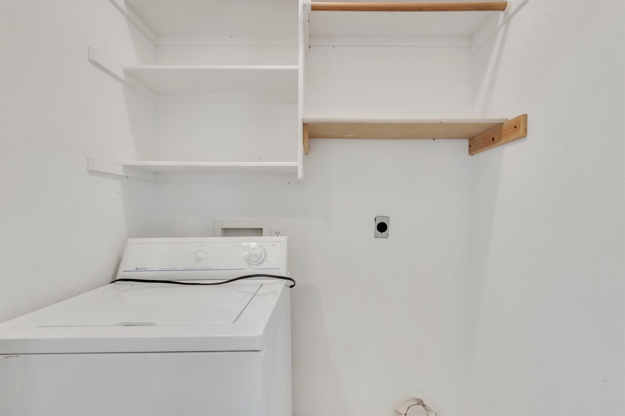 1207 Orlando Road Austin, TX 78733 - Photo 21 of 30 Dedicated laundry area featuring a white washing machine, white wall shelves, a natural wood-finish shelf, and a wood-finish hanging rod