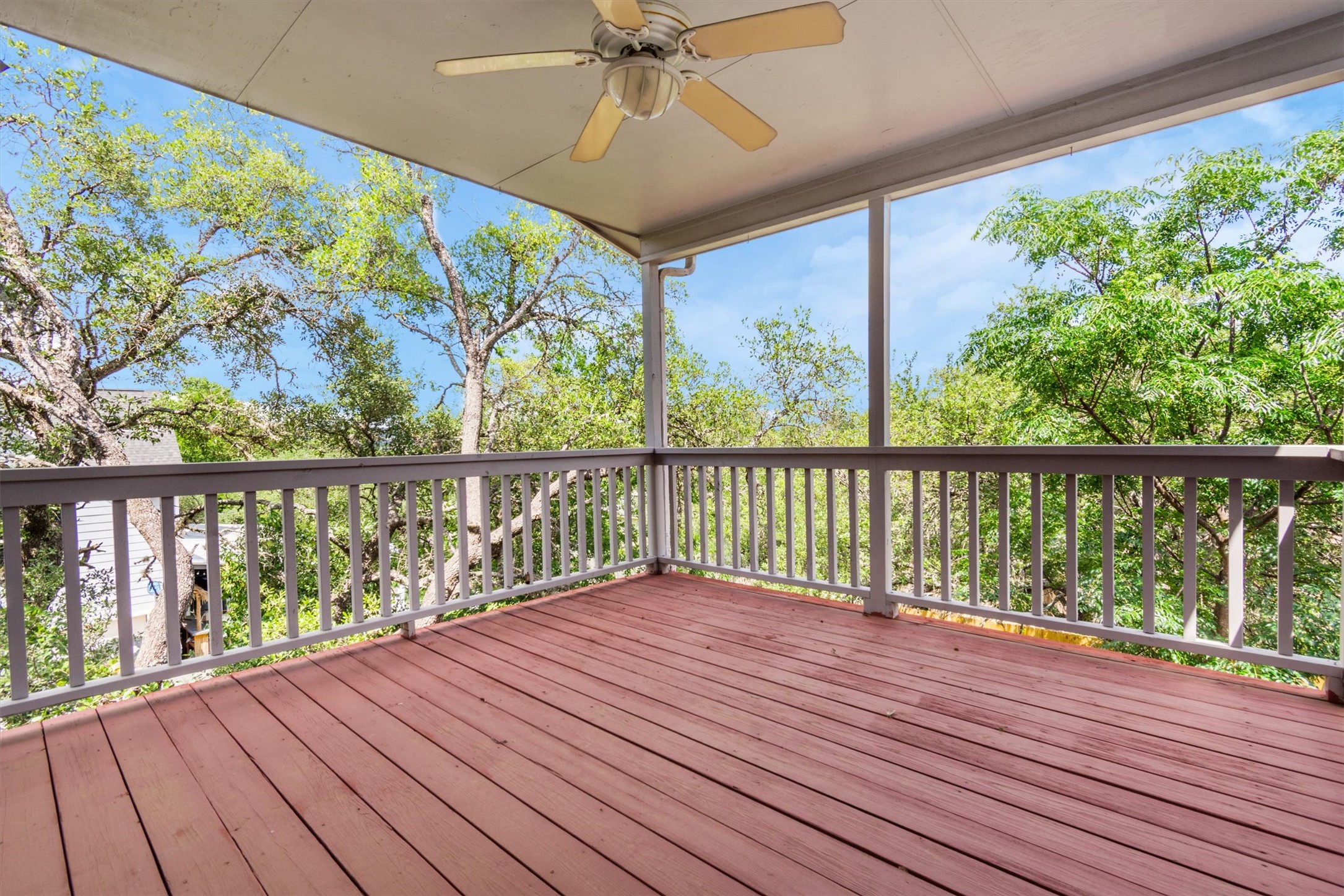1207 Orlando Road Austin, TX 78733 - Photo 22 of 30 Expansive covered deck featuring a ceiling fan, wood-finish flooring, and white railing overlooking mature trees