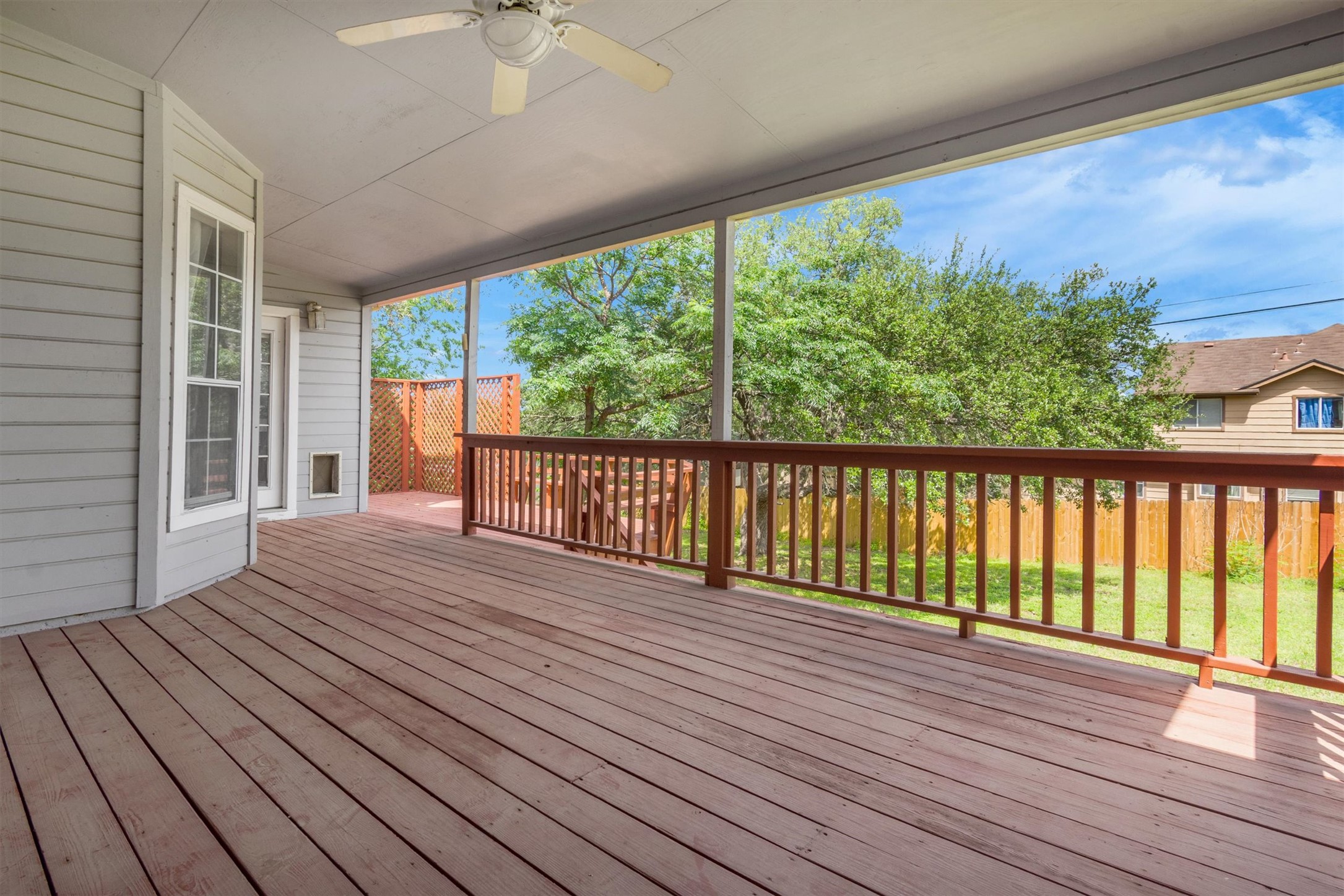 1207 Orlando Road Austin, TX 78733 - Photo 25 of 30 Expansive covered deck featuring wood-finish flooring, a ceiling fan, and a wood railing overlooking a fenced yard with mature trees