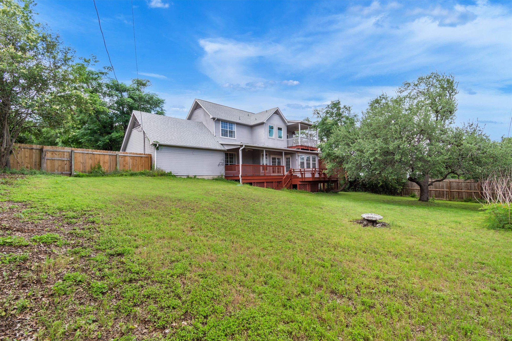 1207 Orlando Road Austin, TX 78733 - Photo 27 of 30 Expansive backyard featuring a mature tree, wood privacy fencing, and a multi-level wood deck