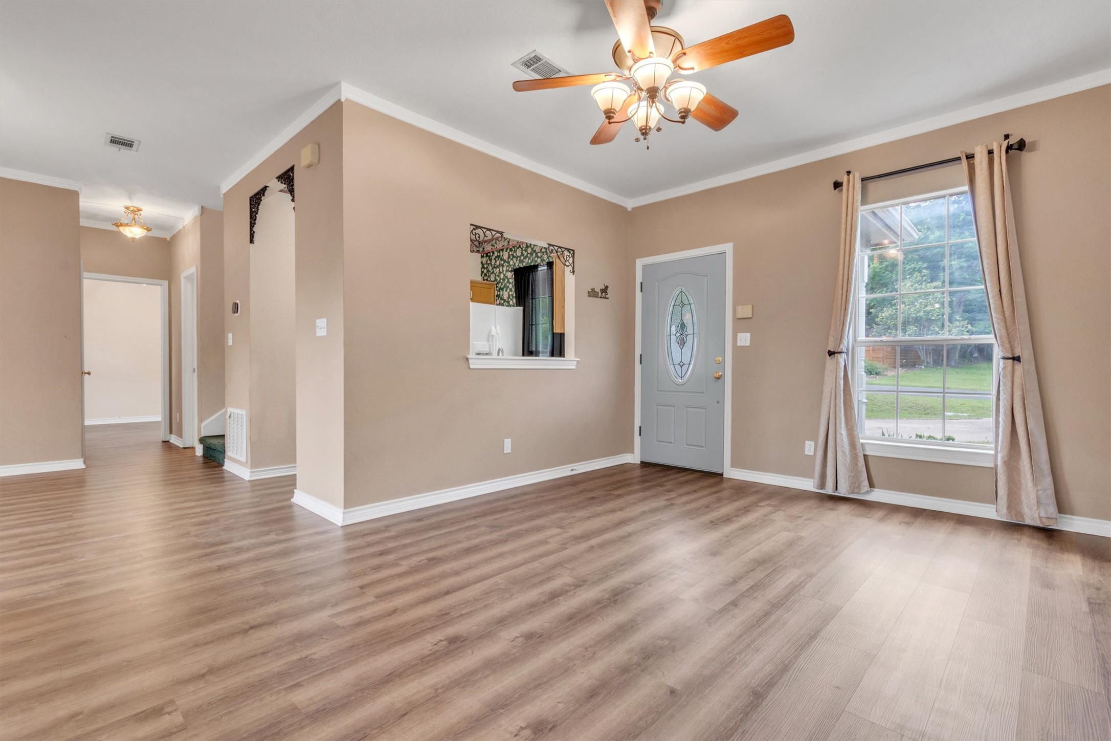 1207 Orlando Road Austin, TX 78733 - Photo 4 of 30 Spacious interior with wood-finish flooring, a decorative ceiling fan, and a light gray front door with an oval-shaped glass insert